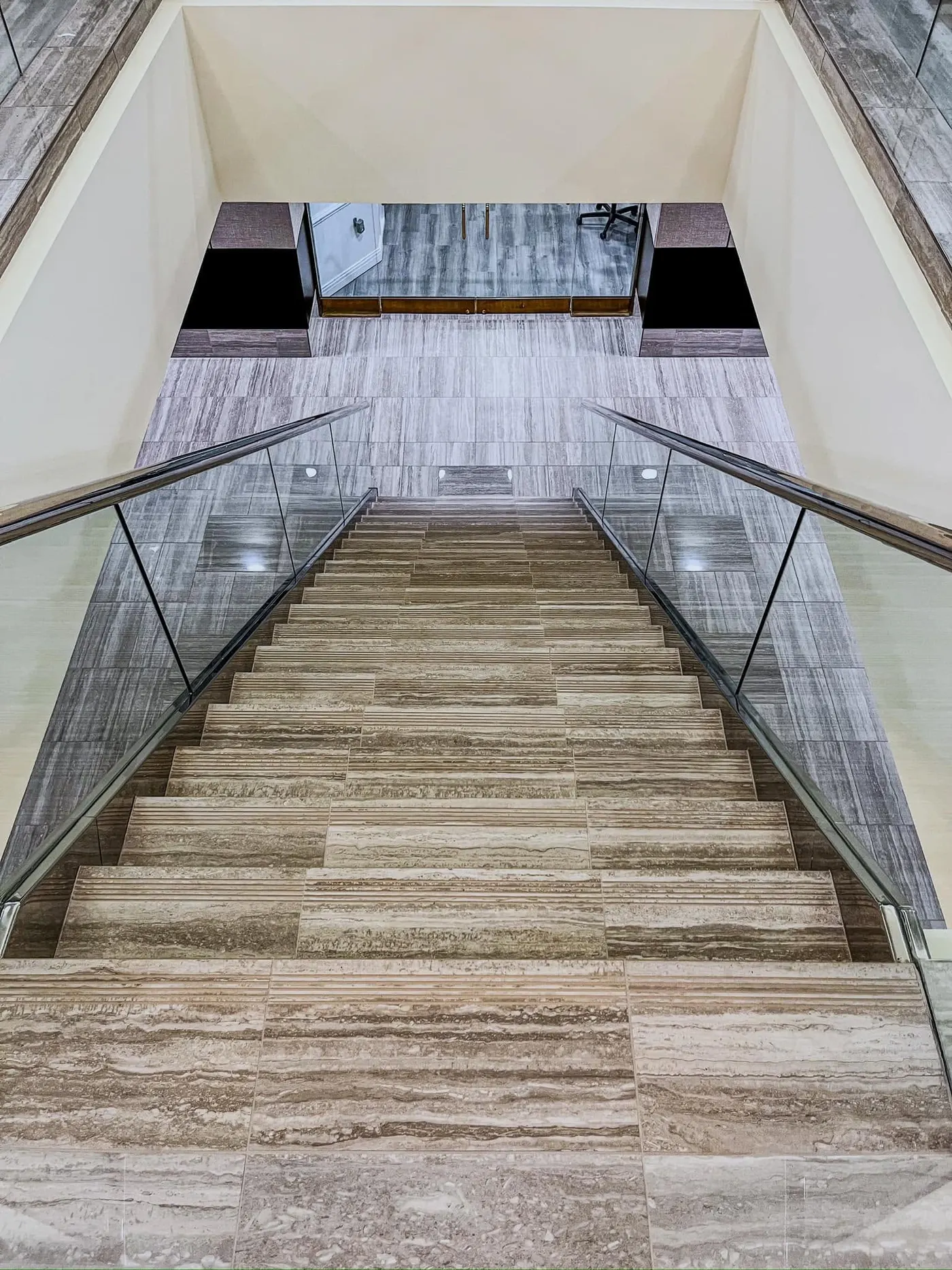 Grand staircase with stone-look treads and glass rails